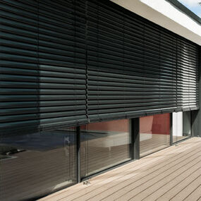 Moderne Außenjalousien an einer großen Fensterfront sorgen für effektiven Sonnenschutz.