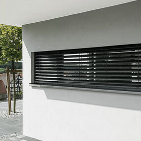 Außenjalousie an modernem Fenster mit Blick auf Terrasse und Garten im Einfamilienhaus.