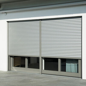 Helle elektrische Rollläden an einer modernen Terrassentür in einem Neubauhaus.